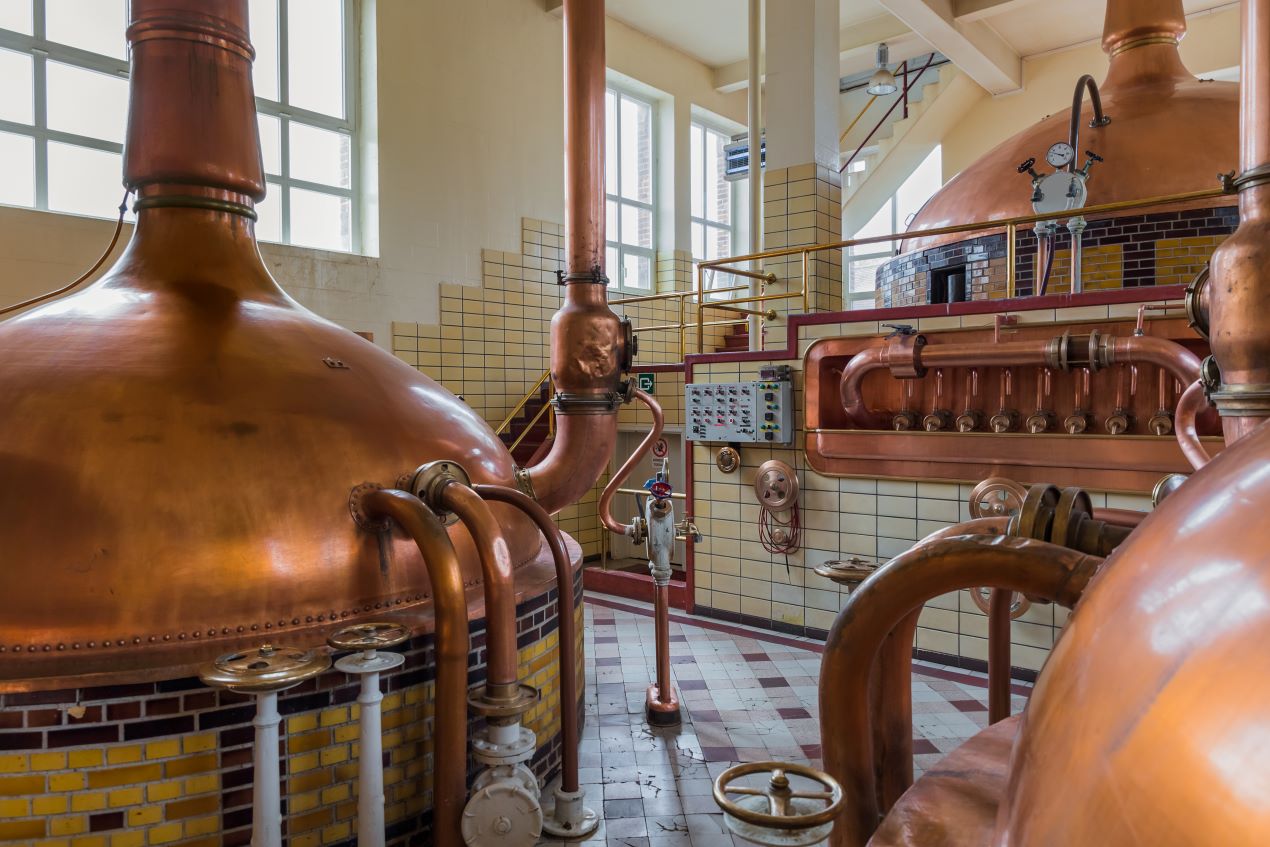 Traditionelle Brauerei mit kupfernen Kesseln, die den handwerklichen Brauprozess von Bieren wie dem Tripel Karmeliet zeigen.