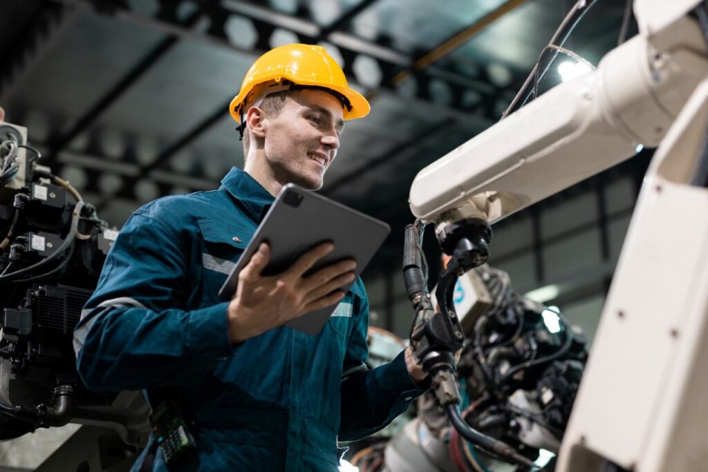 Techniker mit Tablet ueberprueft Palettierer in einer automatisierten Produktionslinie