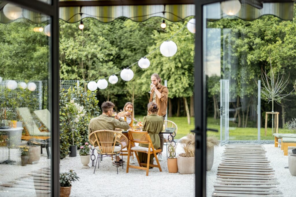 Gruppe von Menschen sitzt im Garten bei Lichterkette | Terrassendacheindeckung