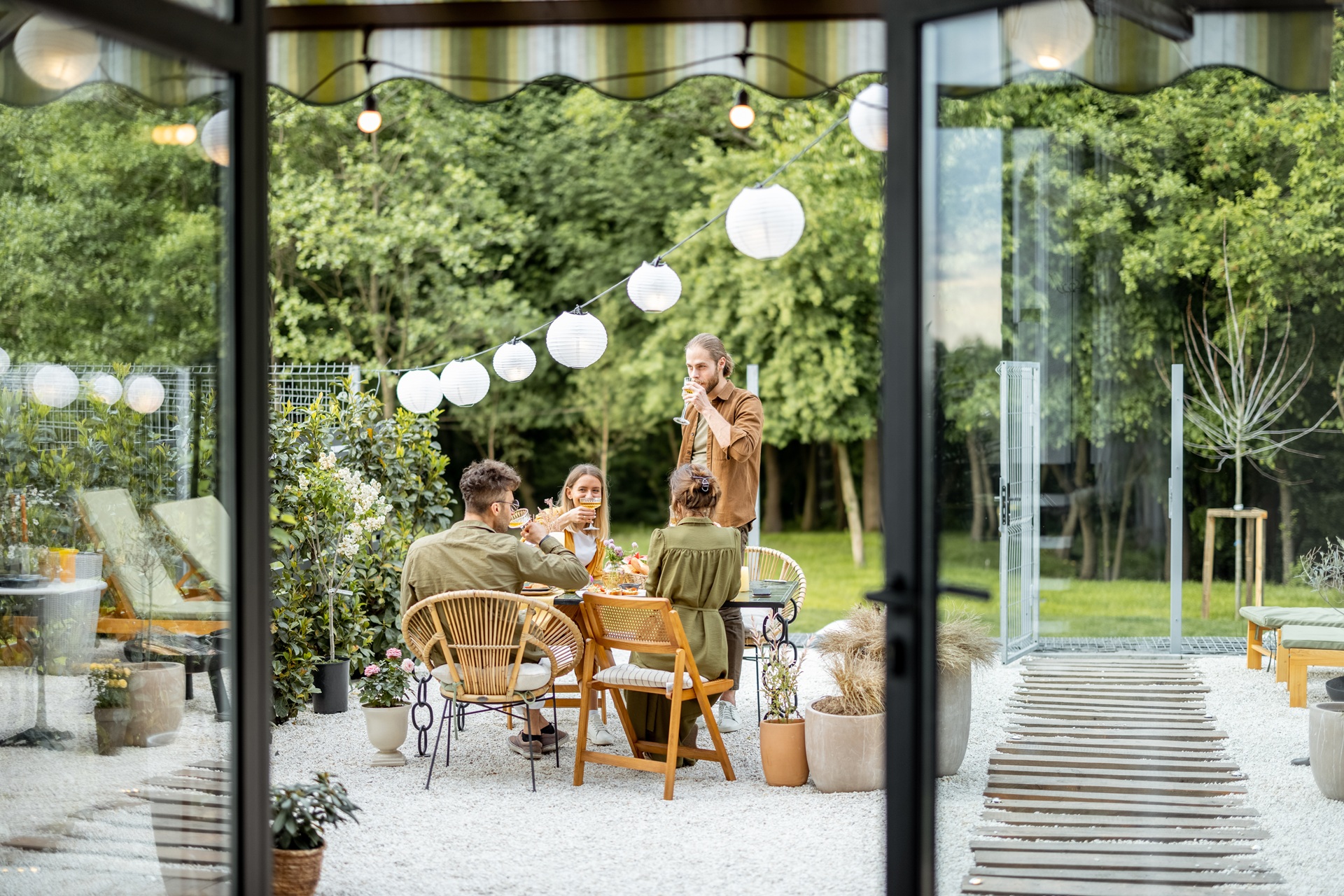 Gruppe von Menschen sitzt im Garten bei Lichterkette | Terrassendacheindeckung