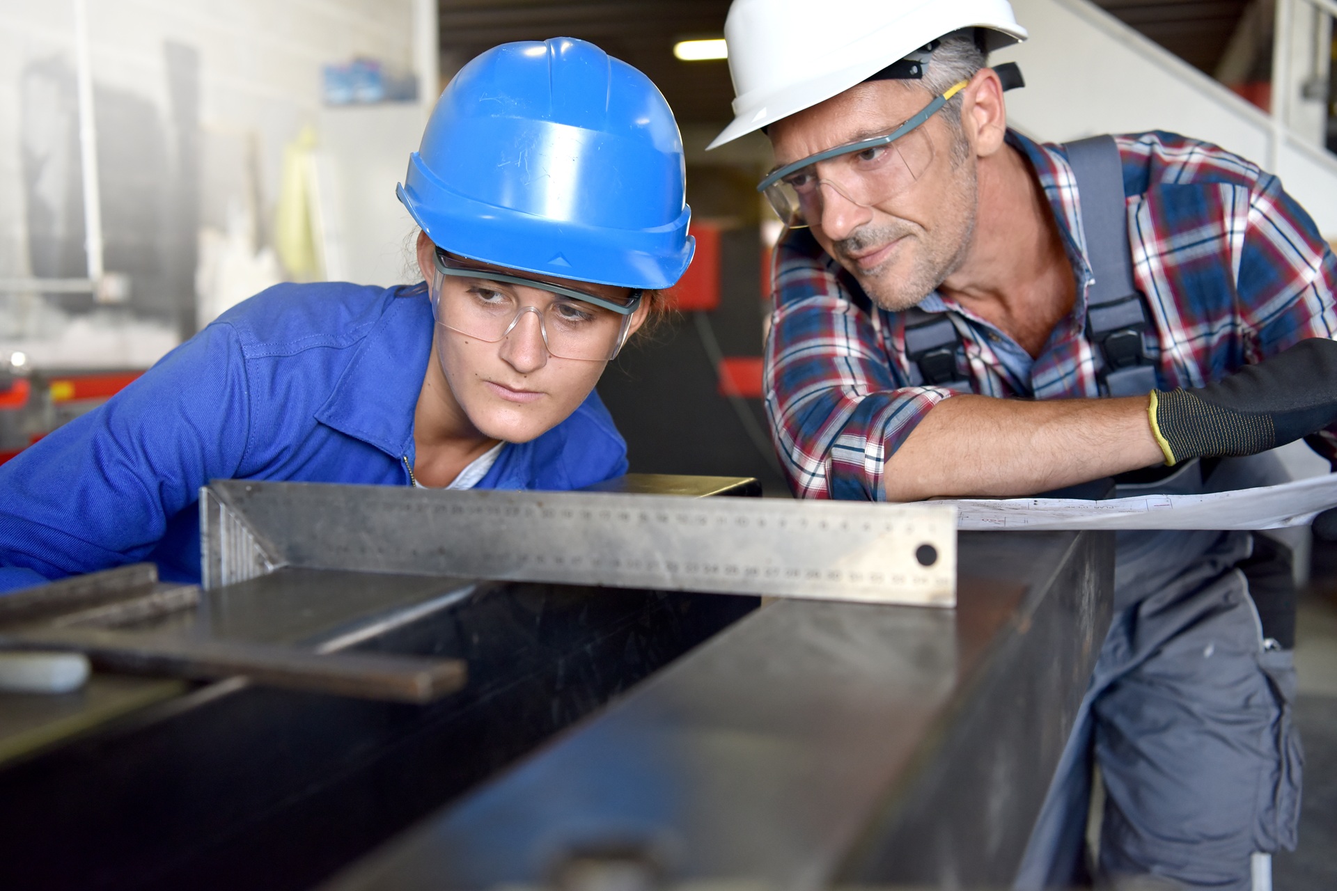 Zwei Personen kontrollieren Metallbauteil mit Winkelmass | Gerüstbanner